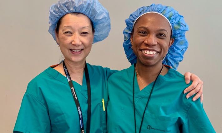two women in green scrubs and blue surgical caps