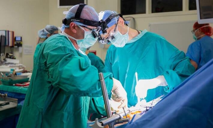 Michael Lidsky, MD, and Justin Barr, MD, work to implant an HAI pump into a patient's abdominal wall.