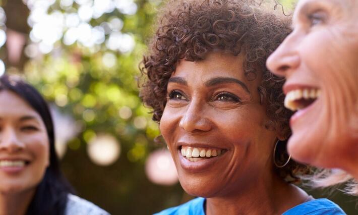 Three women smile together outside