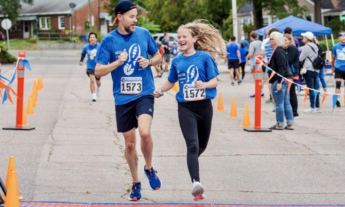Man running with adolescent girl and smiling at each other