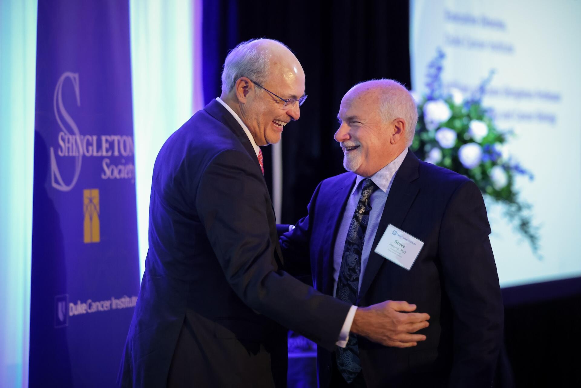 Two men in suits smiling together