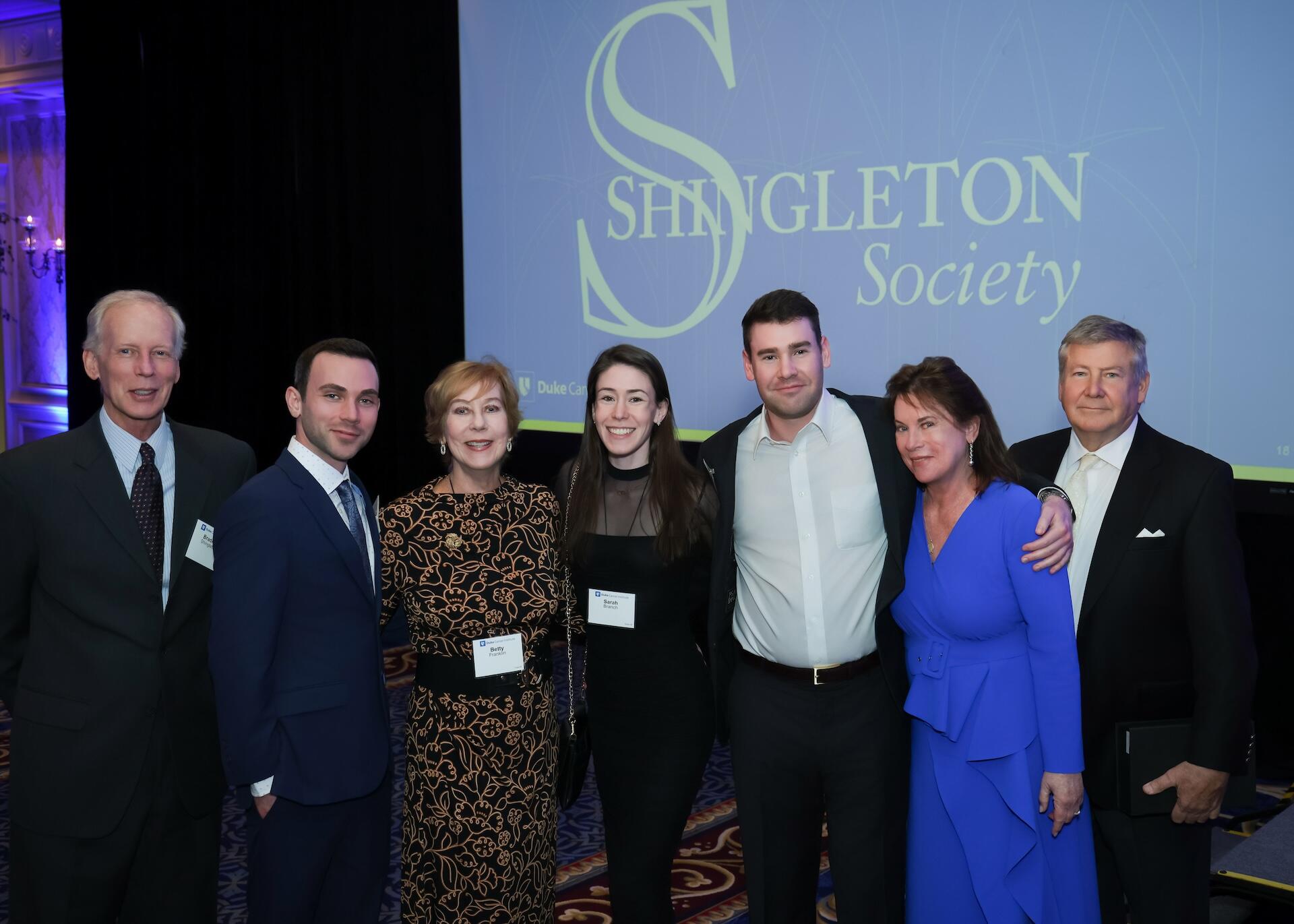 Brad and Catherine Shingleton Branch posing with family members in front of a purple Shingleton award banner.