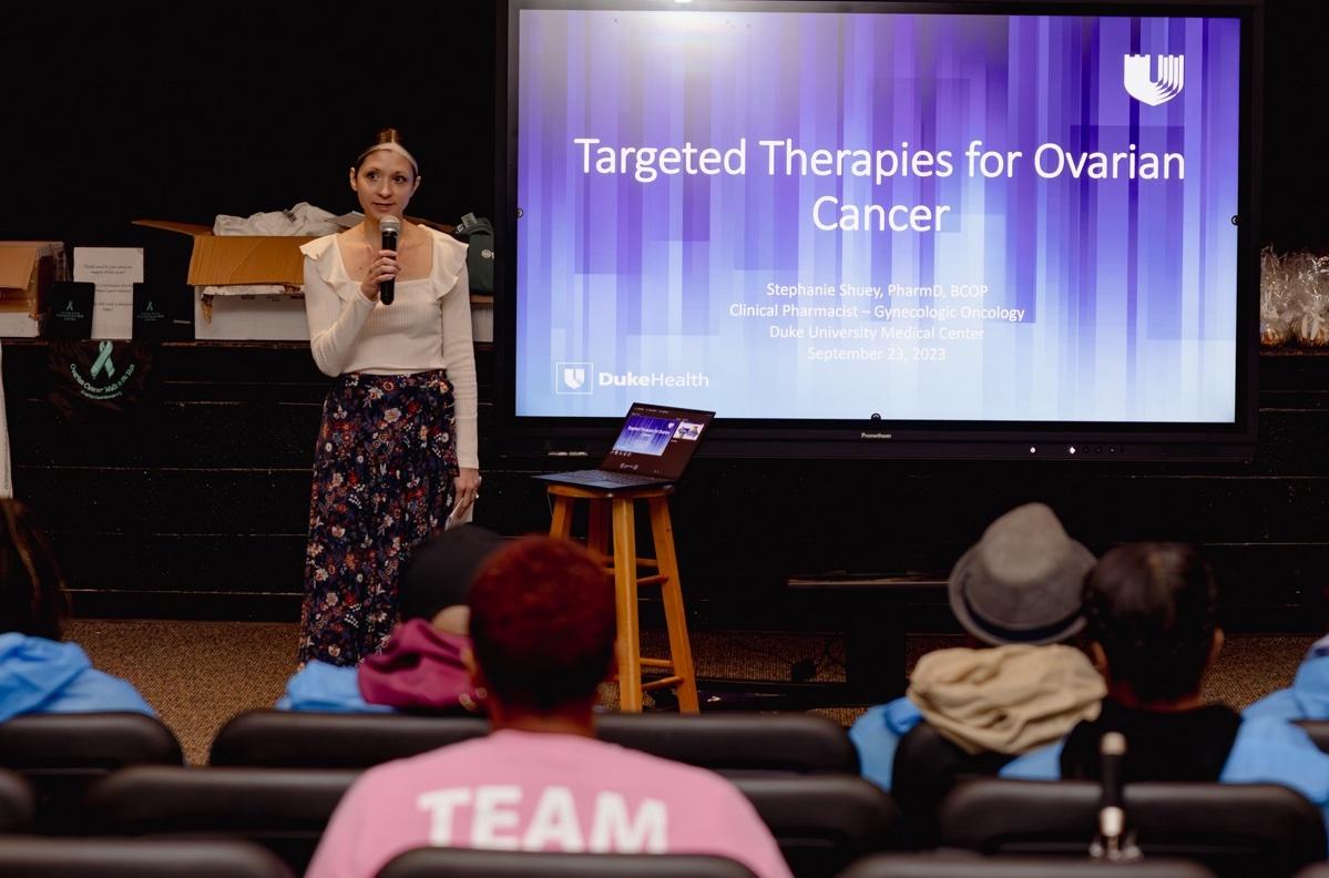 woman holding a microphone beside a screen reading "Targeted Therapies for Ovarian Cancer"