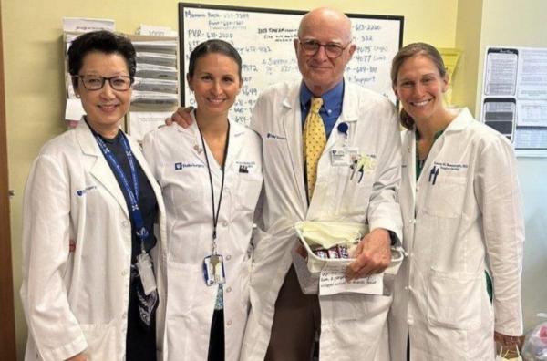 Shelly Hwang, Jennifer Plichta, Gregory Georgiade, and Laura Rosenberger — all in white lab coats — pose in a clinic room 