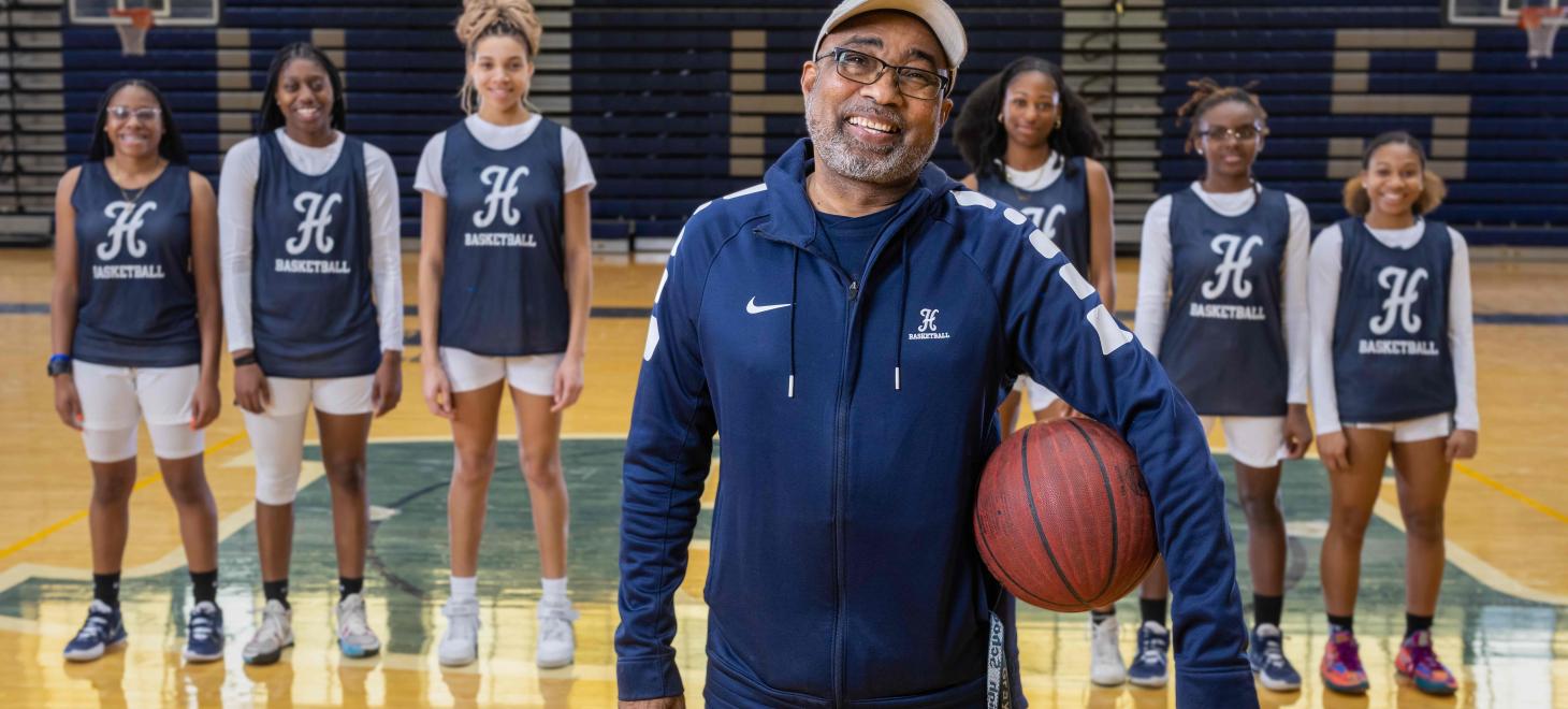 Coach holds basketball in front of his girl's team.