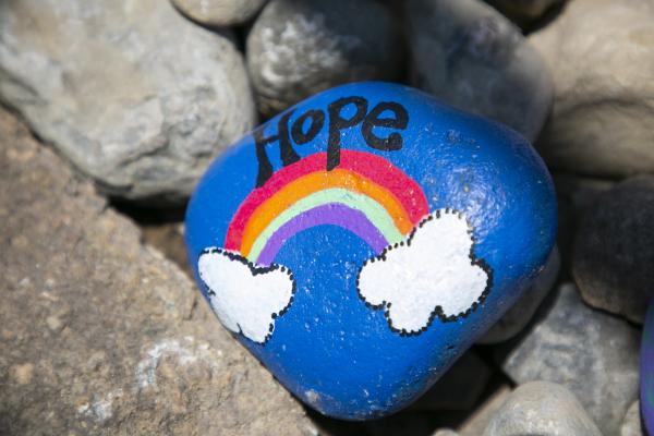 A rock is painted blue with a rainbow and the word "hope"