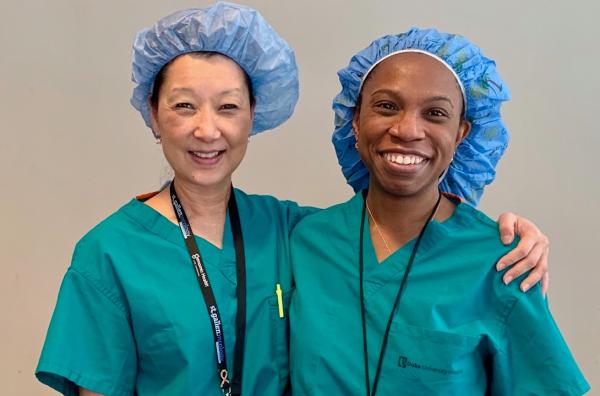 two women in green scrubs and blue surgical caps