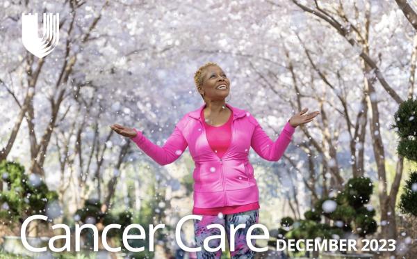 woman in pink hands up and head raised as snow falls down in a tree-filled landscape, and the words Cancer Care December 2023
