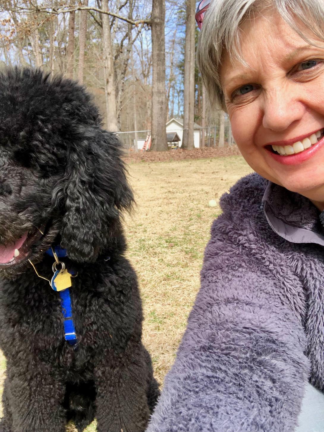 Kathy Jennings takes a selfie outside with her black poodle puppy Cody.