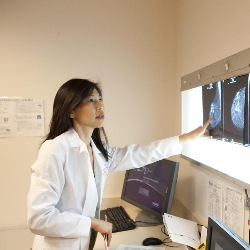 Woman in white doctor coat looking at x-rays