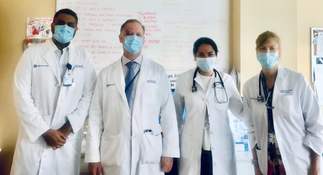 Vijay Paryani, Kelly Marcom, Sarah Sammons, and Susan Dent stand beside each other. All are wearing masks and white lab coats.