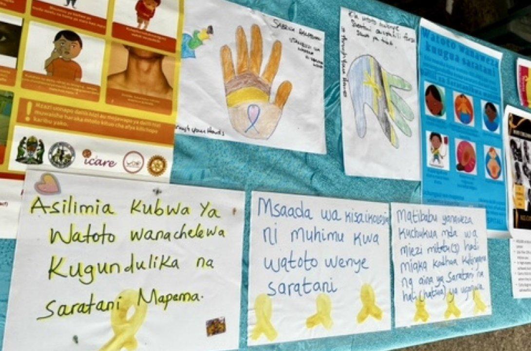 a table of posters made by kids and adults for World Cancer Day 2022