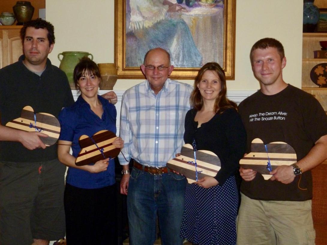 Five people holding wooden cutting boards