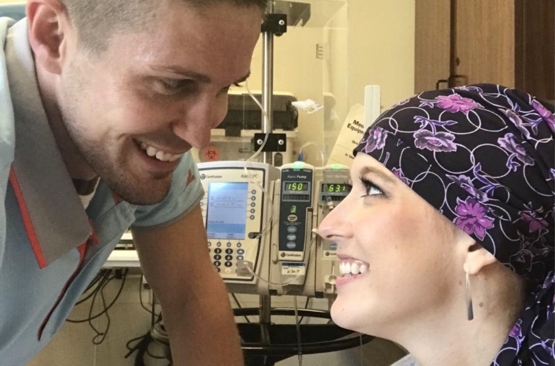 Kortne Waginger, wearing a scarf on her head, looks at her husband in a medical facility.