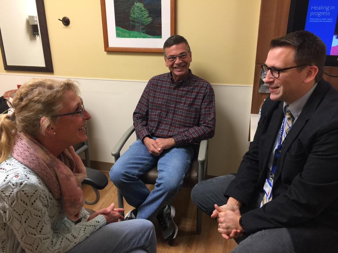 Lisa and Dave VanTress smiling at Dr. Jeffrey Clarke as he speaks to them in a clinic room