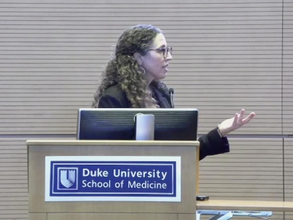 woman in profile at podium labeled Duke University school of Medicine