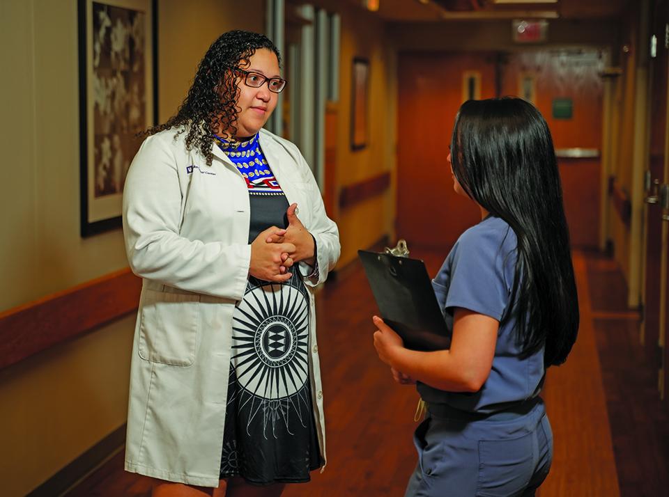 Hannah Woriax, MD, wearing a white coat and speaking with a colleague