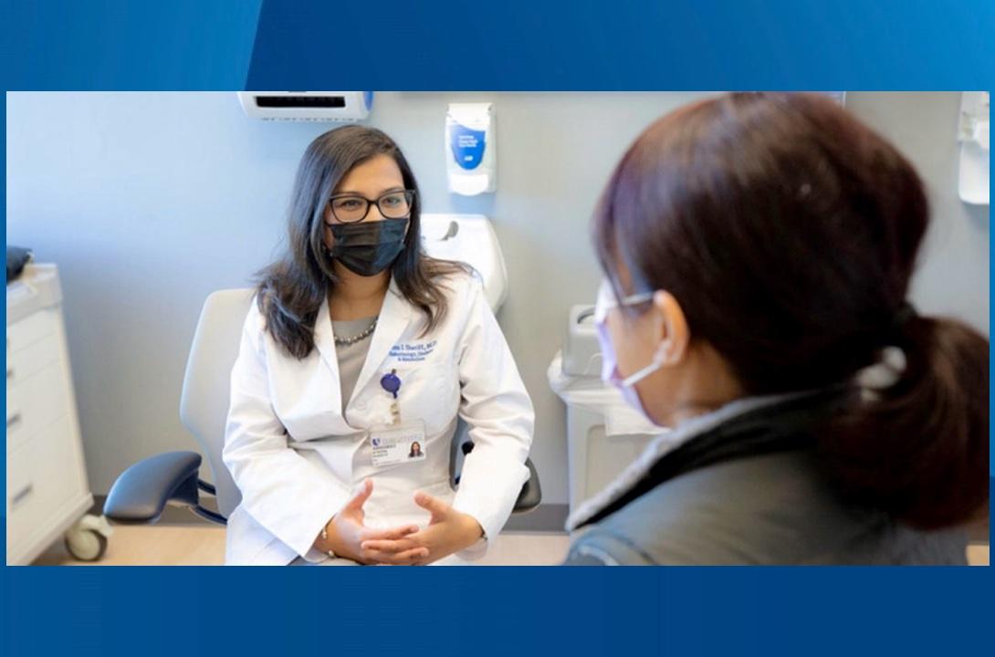 Afreen Shariff, in mask and glasses, speaks with a patient in clinic