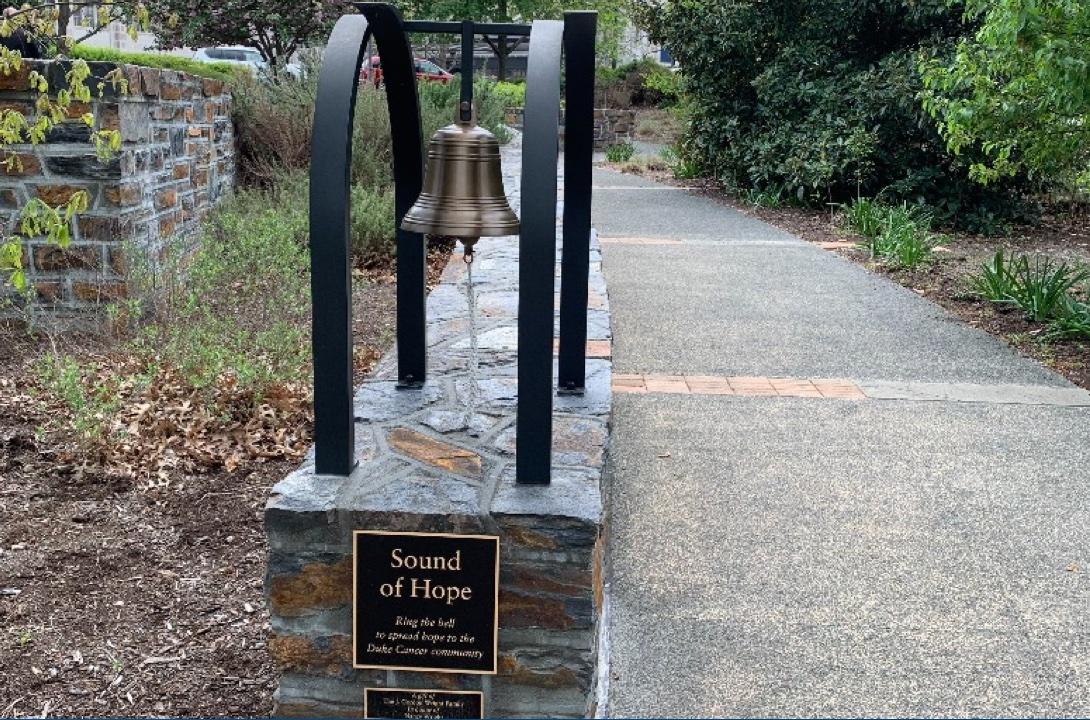 The "Sound of Hope" Bell is hung in a garden area next to a concrete path