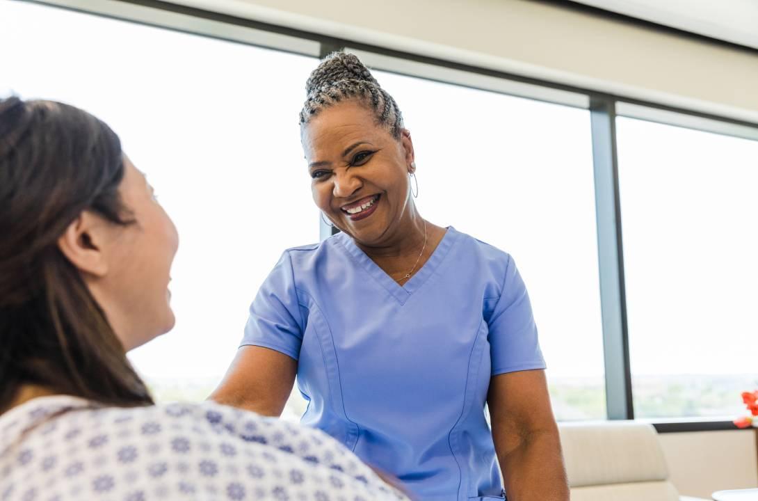 Nurse in blue scrubs smiling at patient
